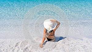 girl with white straw hat relaxes in front of the sea photo